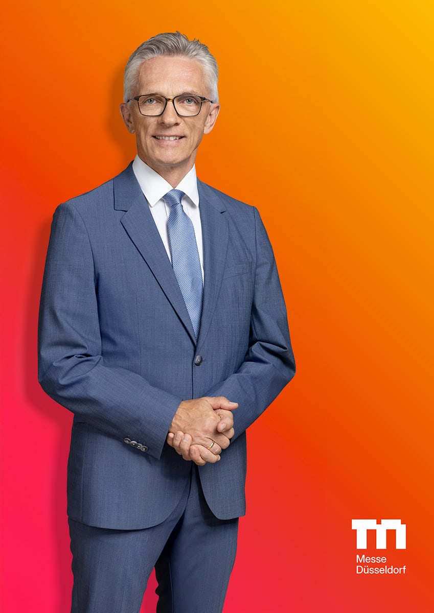Hochwertiges Business-Porträt eines Mannes in Anzug vor buntem Hintergrund.