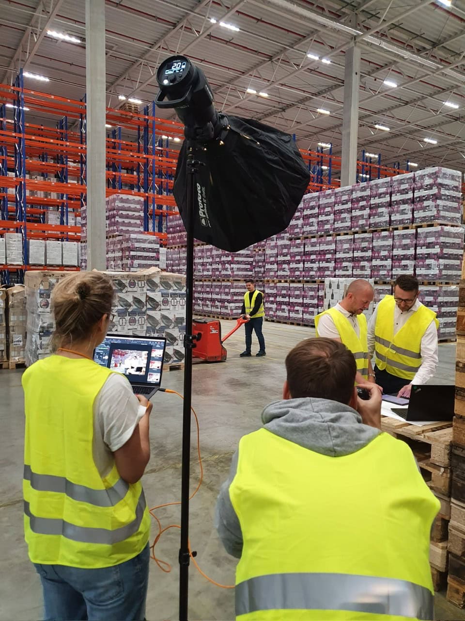 Filmteam bei Dreharbeiten in Lagerhalle mit Beleuchtung und Crew.